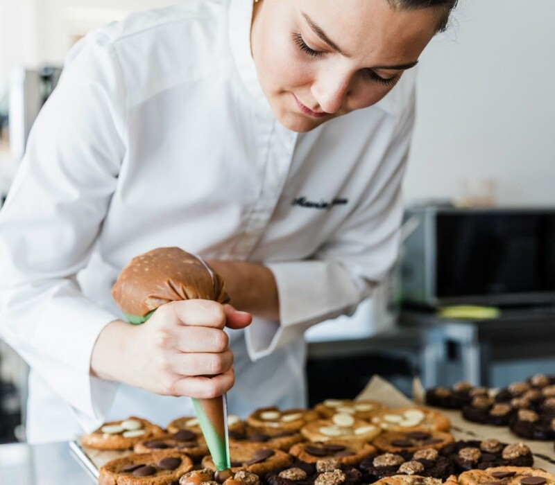Maurine Géron garnissant des cookies à la poche à douille dans son atelier