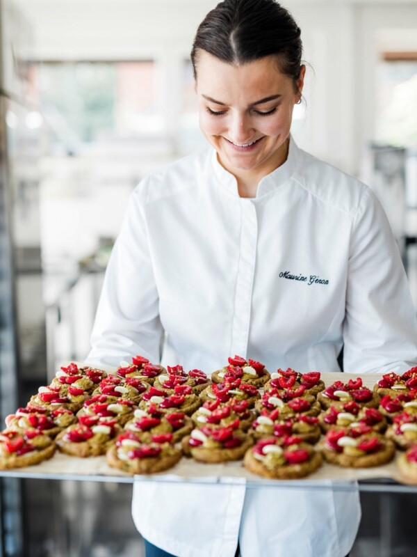 Maurine Géron souriante, tenant un plateau de cookies pâtissiers aux framboises